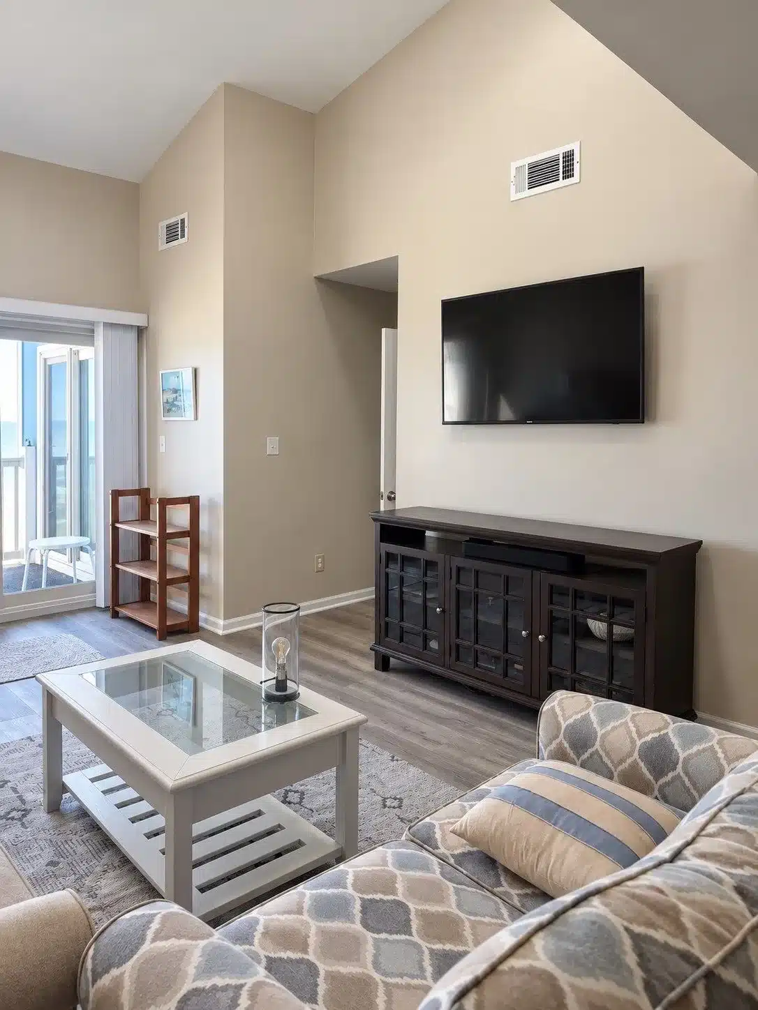 Beige Living Room With Vaulted Ceiling Beige-painted living room with vaulted ceiling, white trim, dark wood media console, and glass coffee table.