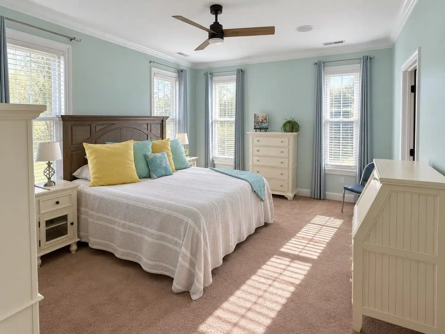 Mint Green Bedroom Paint Mint green painted bedroom walls with white ceiling, trim, dark wood bed frame, cream cabinetry, and multiple windows.